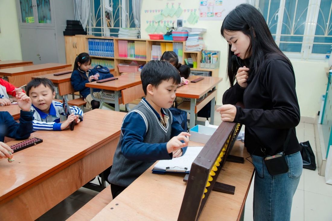 Giáo viên hướng dẫn một bạn nhỏ gảy bàn tính